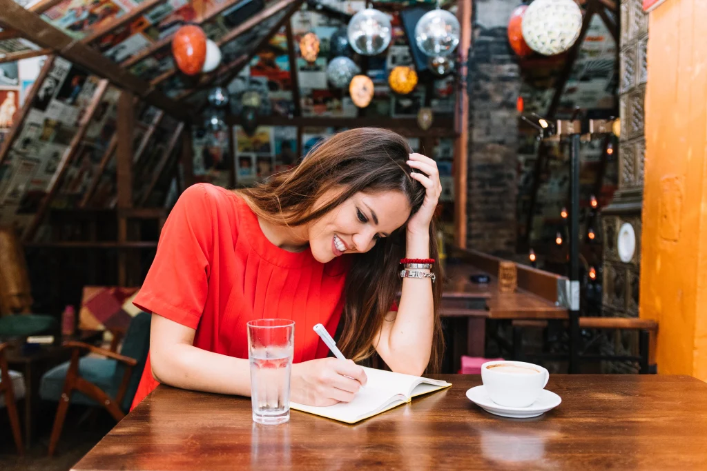 smiling-woman-writing-schedule-diary-with-cup-coffee-desk